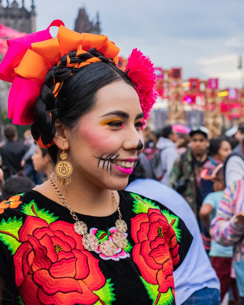 Women smiling away from the camera dressed in traditional Mexican outfit for day of the dead festival (dia de los muertos).